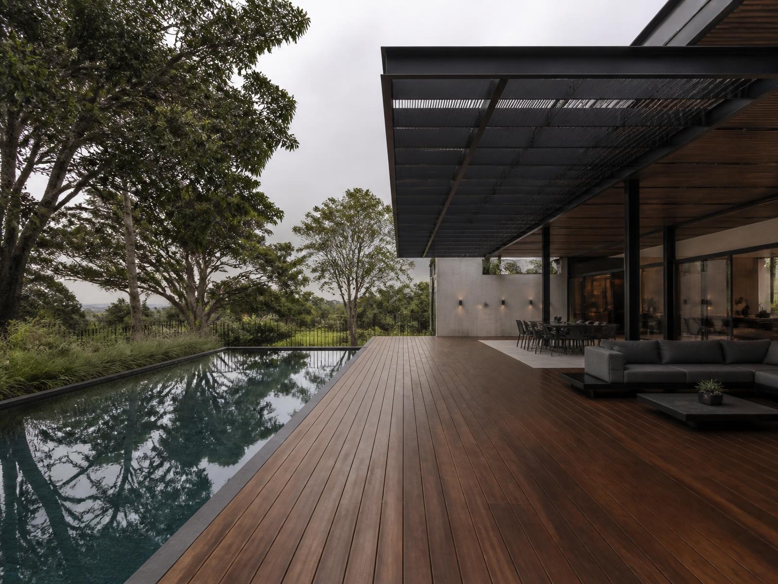 Hardwood pool deck with a black steel shade structure at a modern residence